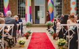 A wedding ceremony set up with chairs, a red carpet and colourful columns.