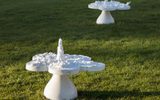 Two small sculptures of mushroom-like shapes made of white material sit on the grass.