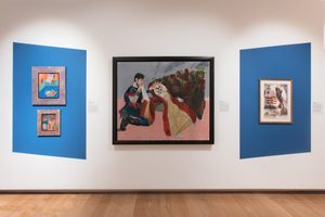 Four paintings hang on a wall with a white and blue background inside an exhibition space with a wooden floor.