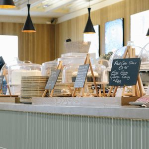 A cafe counter with mint green tiles showing cakes and pastries