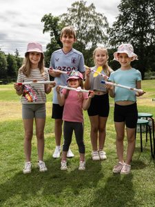 CA3465 A group of five children stand outside on the lawn each holding a rocket made out of paper.