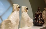 This image shows two porcelain dogs sat symmetrically next to each other next to other historical objects.