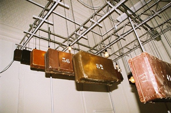 Hanging metal containers or buckets of various colors in a warehouse or industrial setting.