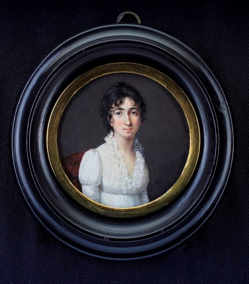 A framed oval portrait painting of a woman with curly hair wearing a white dress with a red shawl against a dark background.