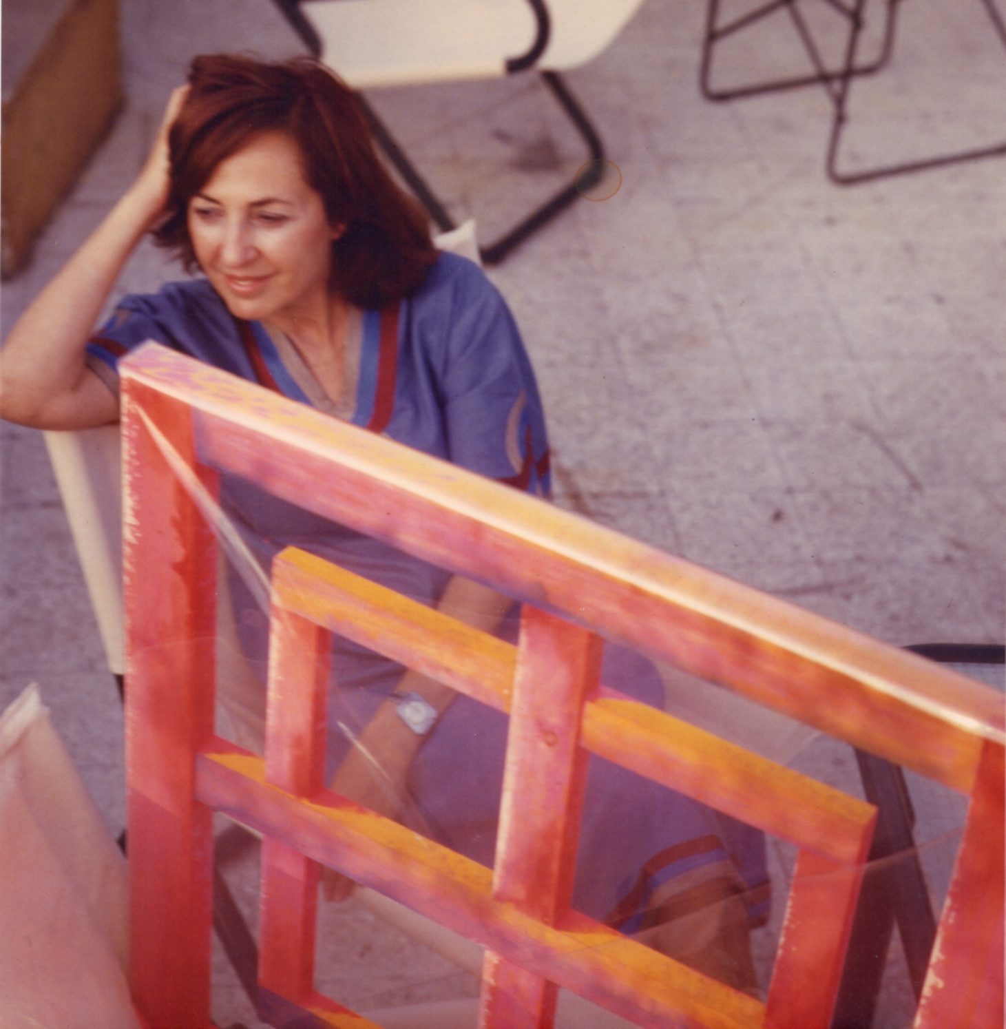 Carla Accardi sits beside a brightly coloured red, orange and yellow structure on a terrace, with chairs visible in the background.